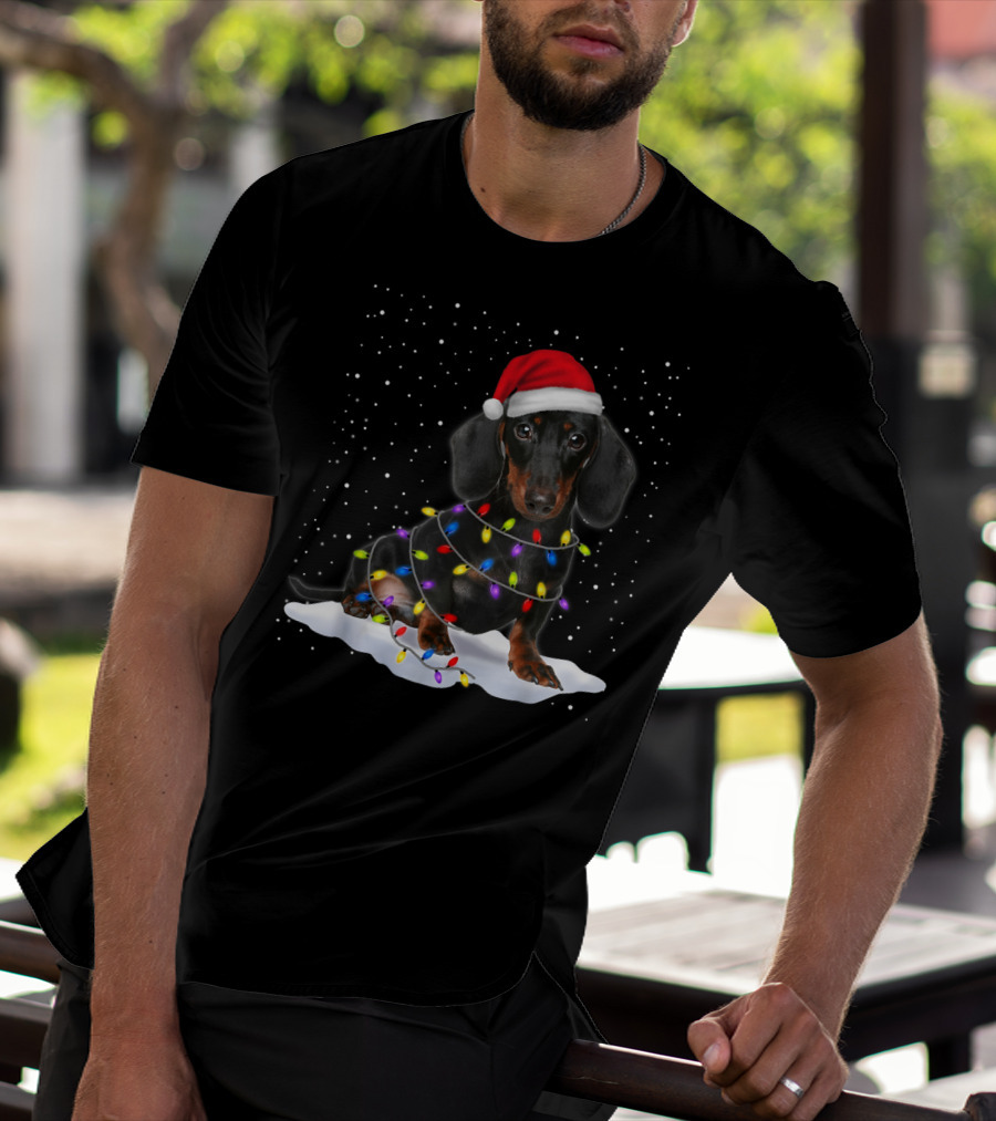 Dachshund Santa Hat Wrapped In Christmas Tree Lights In Snow With Falling Snowflakes T-Shirt