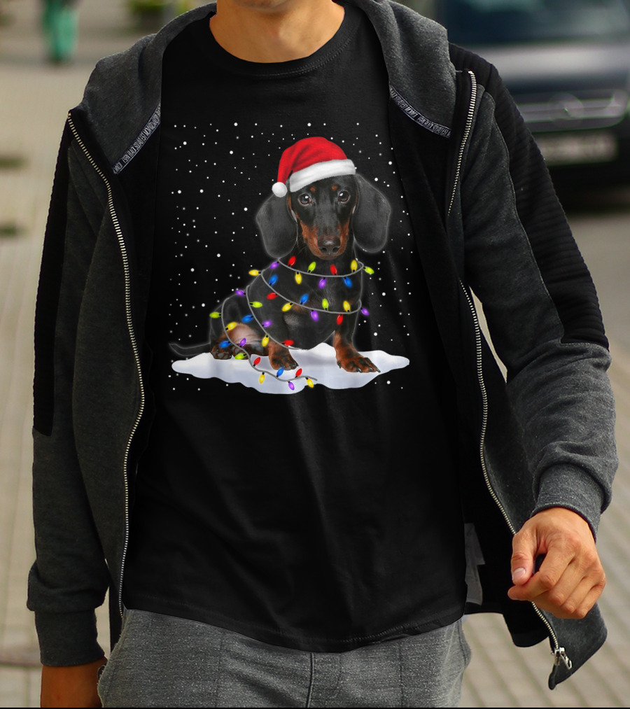 Dachshund Santa Hat Wrapped In Christmas Tree Lights In Snow With Falling Snowflakes T-Shirt
