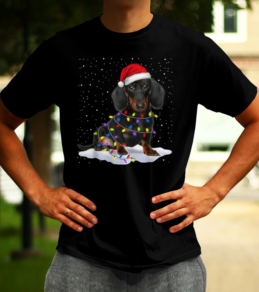 Dachshund Santa Hat Wrapped In Christmas Tree Lights In Snow With Falling Snowflakes T-Shirt