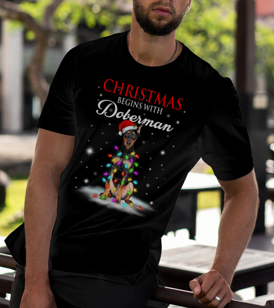 Christmas Begins With Doberman Wrapped In Holiday Lights And Santa Hat Snowflakes T-Shirt