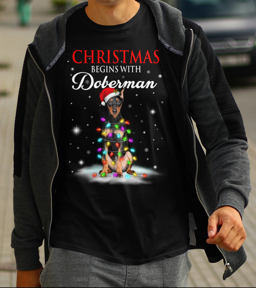 Christmas Begins With Doberman Wrapped In Holiday Lights And Santa Hat Snowflakes T-Shirt